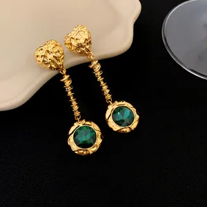 Vue détaillée de boucles d'oreilles vintage plaquées or avec gemme vert émeraude et motif cœur