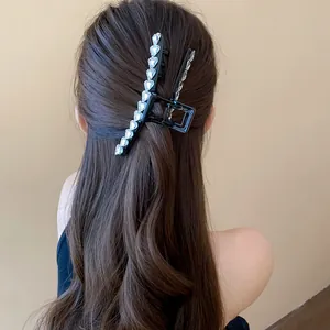 Detailed view of elegant black hair claw clip with rhinestones on female model's back hair