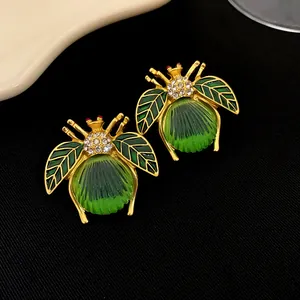 Vue détaillée de boucles d'oreilles insectes vintage dorées avec émail vert et cristaux