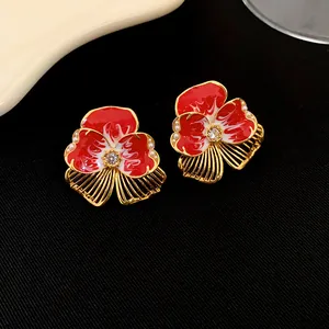Gros plan de boucles d'oreilles fleur rouge vintage avec perles et élégant plaqué or.