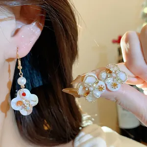 Close-up view of elegant gold floral earrings with pearls and stones worn on the ear