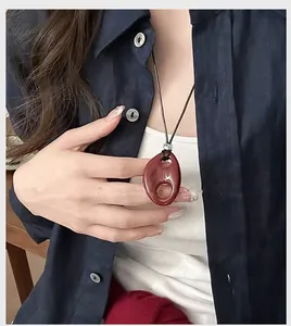 Close-up of a vintage-style reddish resin hollow oval pendant necklace on a model.