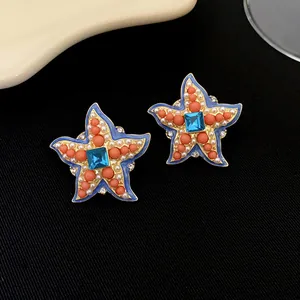 Gros plan de boucles d'oreilles étoile de mer vintage dorées avec perles et gemmes bleues