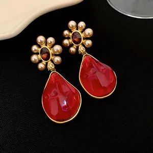 Gros plan de boucles d'oreilles vintage plaquées or avec pendentifs gouttes rouges et perles