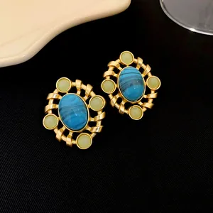 Gros plan détaillé de boucles d'oreilles vintage plaquées or avec pierre bleue et gemmes.