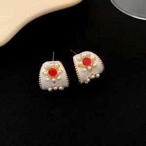 Vue détaillée de boucles d'oreilles vintage dorées avec perles et centre en émail rouge