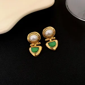 Gros plan de boucles d'oreilles vintage dorées avec perles et pierres vertes.