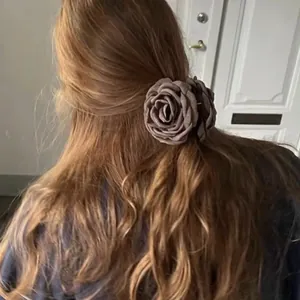 Macro view of a vintage brown fabric rose hair claw clip worn on long wavy hair.