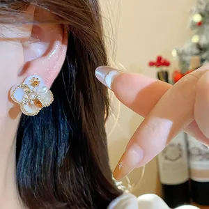 Detailed close-up of 18K gold plated zircon and pearl flower earring on a model ear