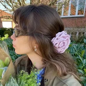 Elegant large lavender fabric flower hair clip accessory styled on wavy brown hair