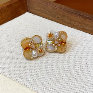 Close-up of vintage flower earrings with 18K gold plating, pearls, and amber zircons