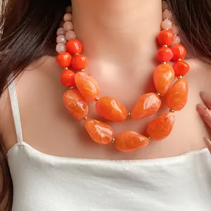 Nahaufnahme einer leuchtend orangefarbenen Acrylperlenkette mit Muscheltextur am Model