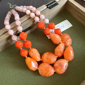 Nahaufnahme einer mehrlagigen Acrylperlenkette mit oranger Marmortextur und rosa Perlen