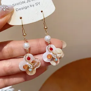 Close-up detail of retro palace style 18K gold-plated flower earrings with white pearls
