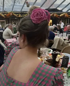 Lifestyle view of an elegant pink fabric rose hair clip worn on a twisted bun style