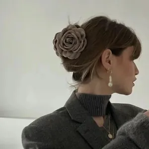 Elegant fabric rose hair claw clip worn on a low bun by a female model