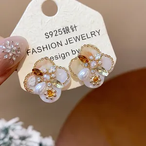 Close-up detail of vintage style flower stud earrings with pearls and 18K gold plating