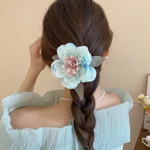 Back view of a model wearing a delicate light blue and pink fabric flower hair clip