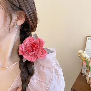 Close-up of a pink cloth flower hair clip styled on a side braid for a sweet look.