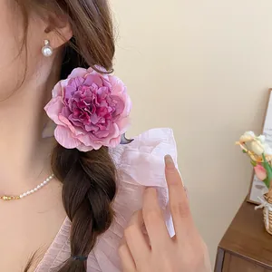 Detailed macro shot of a large purple fabric flower hair clip worn on a braided hairstyle