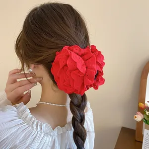 Detailed close-up view of a large red lace flower hair claw clip on braided hair