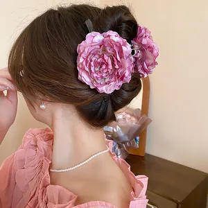 Detail showing a large pink fabric flower hair claw clip on an elegant hair bun