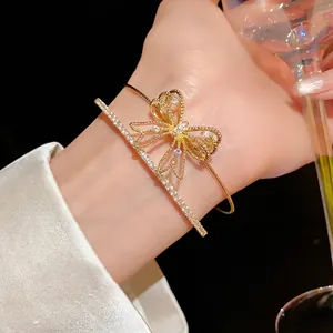 Pulsera de doble capa con lazo de circonita dorada usada con elegancia en la muñeca