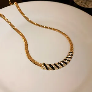 Elegant gold-plated necklace with black enamel stripes and sparkling rhinestones detail