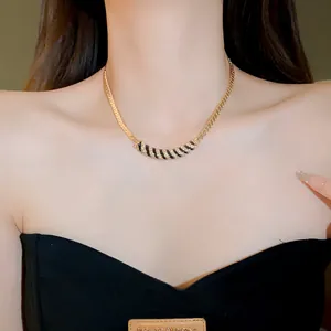 Detailed view of gold-plated necklace with enamel and rhinestones on model.