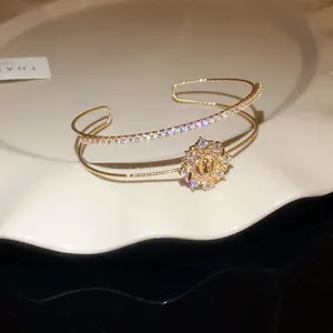 Primer plano de un brazalete dorado de doble capa con pavé de circonitas y motivo