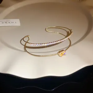Detalle de una pulsera dorada de doble capa con brillantes circones blancos y amarillos