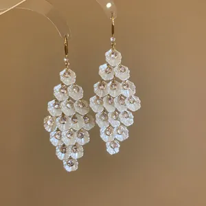 Detailed view of layered white shell petal earrings with zircon accents and gold hooks