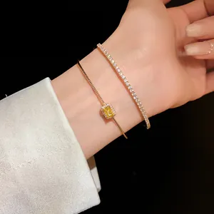 Detalle de elegantes pulseras de oro con gema amarilla y circonitas en la muñeca