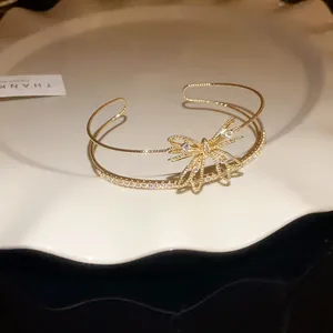 Vista detallada del brazalete dorado de dos capas con un diseño de lazo de circón.