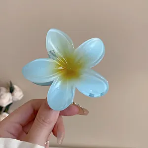 Close-up view of a translucent light blue flower hair claw clip with a yellow center