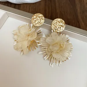 Macro detail of elegant fabric flower earrings with textured gold studs and chiffon petals