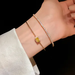 Primer plano de pulseras doradas de doble capa con gema amarilla y circonitas en la muñeca