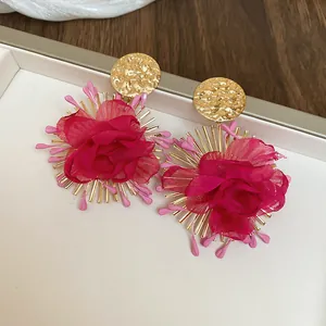 Detail view of handmade magenta fabric flower earrings with elegant hammered gold studs
