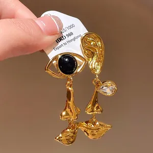 Vintage style asymmetric gold dangle earrings featuring eye, ear, and mouth motifs