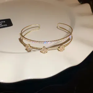 Detailed view of gold zircon bangle with clover flower design and sparkling stones