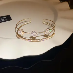Macro detail shot of elegant gold bracelet featuring sparkling zircon flowers and charms