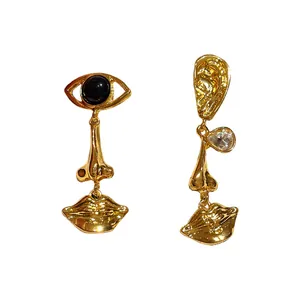 Vintage gold asymmetric earrings with surrealist eye and mouth long drop designs.