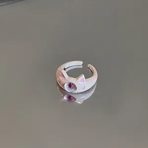 Close-up detail of a cute cartoon cat eye open ring featuring a purple bead on gray background
