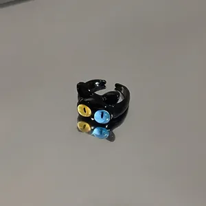 Cute cartoon black cat open ring with yellow and blue eyes on reflective surface