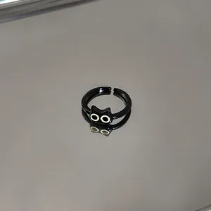 Close-up of a cute black cartoon cat adjustable open ring on a reflective surface.