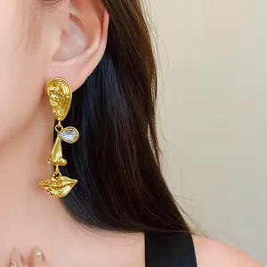 Detail of gold vintage asymmetrical drop earring with abstract eye and lip design