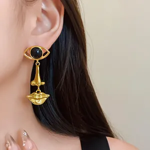 Close-up of vintage gold abstract face earring with eye nose and mouth pendants