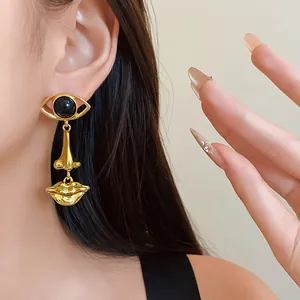 Close-up of surrealist eye nose mouth drop earrings in gold finish