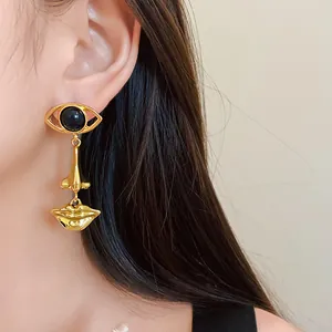 Close-up of gold abstract face drop earring with eye, nose, and lips design on ear.