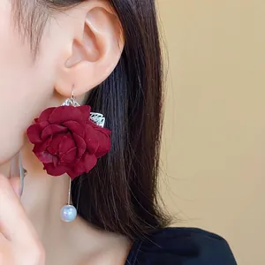 Elegant dark red fabric rose earrings with artificial pearl dangle on model's ear